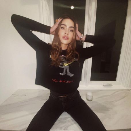 Amelia Hamlin poses a picture in a black t-shirt and a black pant.